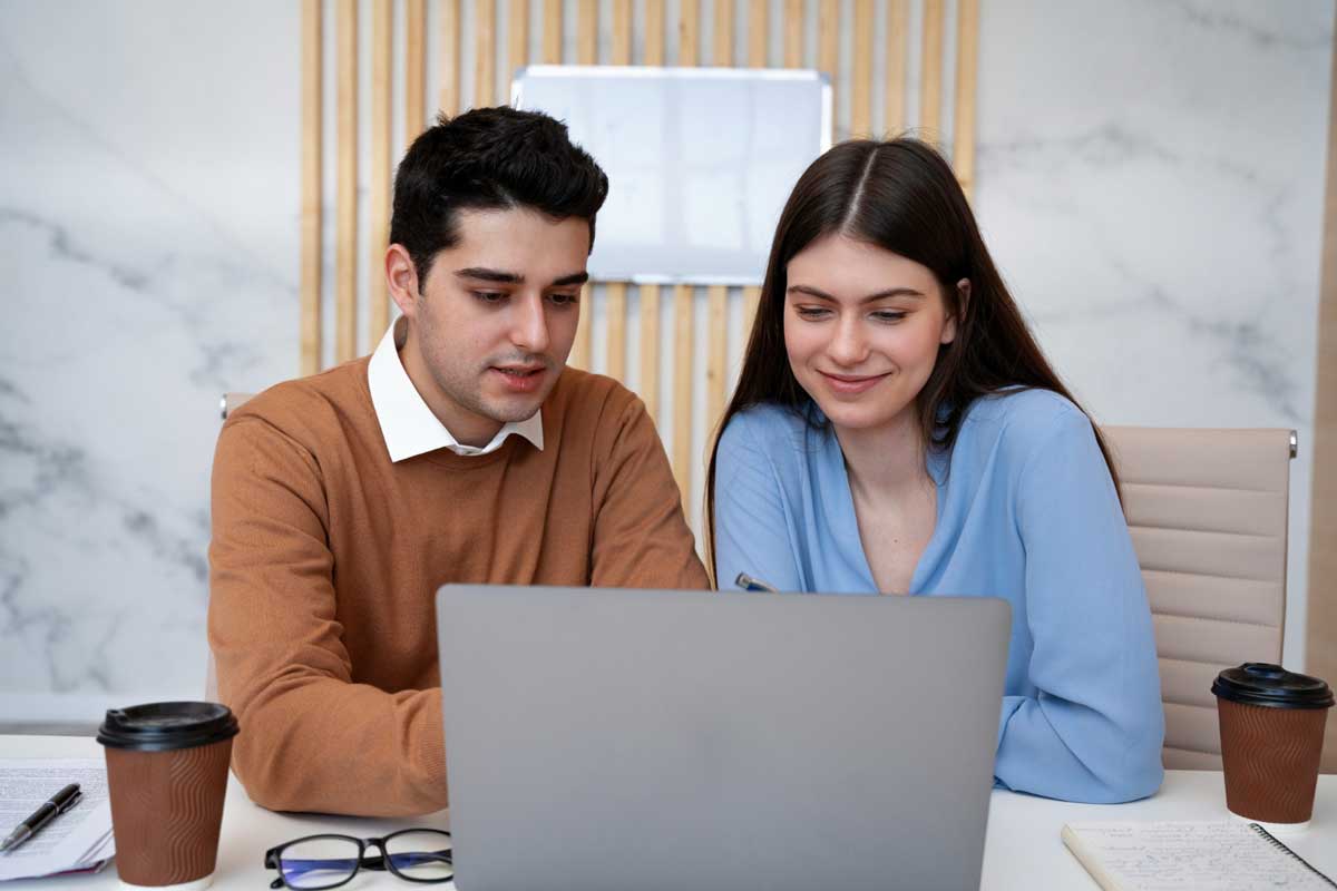 A young girl and boy working together during their internship, engaged in a professional task or discussion in an office environment.